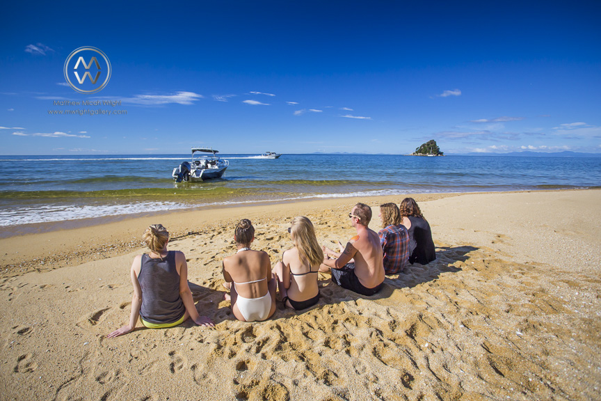 Girls in bikini's play on the golden sand beaches of the Able Tasman National Park.