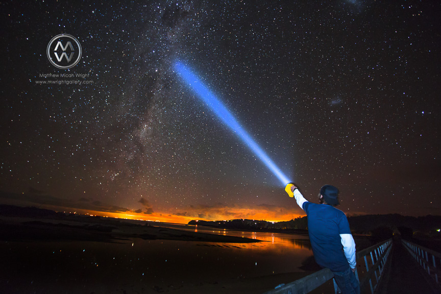 A man shines his flashlight into the starry sky in the Able Tasman National park.