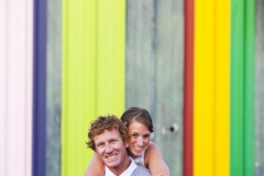 A couple playfully pose for a photograph in front of a vibrant and colorful background in Costa Mesa, California.