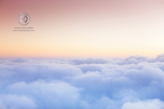 Soft clouds blanket the sky on an international flight.