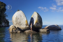 A woman poses in front of one of New Zealand's famous landmarks; Able Tasman National Park's Split Apple Rock.