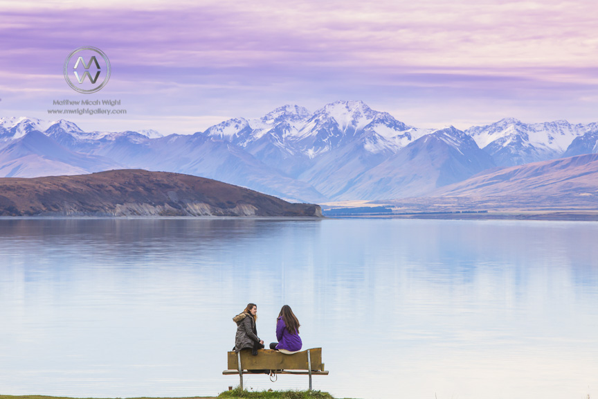 Girls sit lakeside to admire the view of Lake Tekapo.
