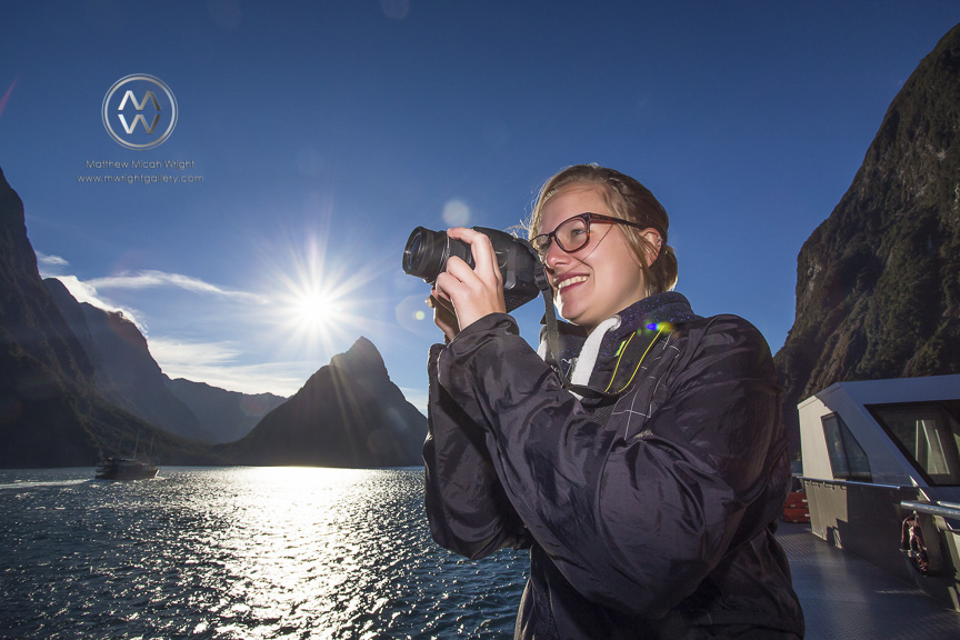 A girl poses for  a photograph in the Milford Sound National Park with the iconic Mitre Peak in the background.