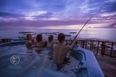 A  man fishes from a spa pool at sunset on the New Zealand coastline in the city of Te Kaha.