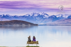 Girls sit lakeside to admire the view of Lake Tekapo.