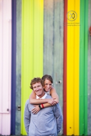 A couple playfully pose for a photograph in front of a vibrant and colorful background in Costa Mesa, California.