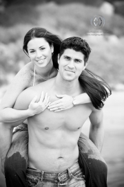 A young couple poses for piggyback portraits on the beach in Encinitas, California.