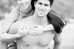 A young couple poses for piggyback portraits on the beach in Encinitas, California.