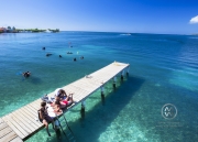 Girls play music and enjoy the sun on a Utila dock in front of Trudy's Hotel.