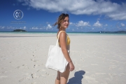Sailing through the Whitsunday Islands to the white silica sands of Whitehaven Beach is a popular activity in Australia. A girl walks along the white sand beach.