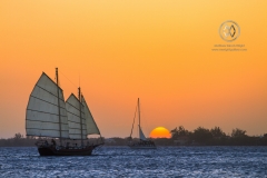 A sailboat crosses the Utila harbor at sunset.