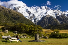 A woman admires the beauty of Mount Cook from the village at the bottom.